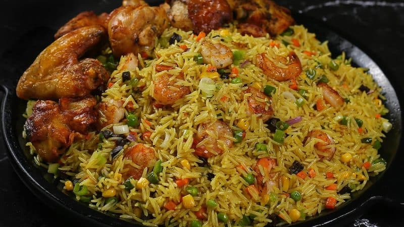 Shrimp fried rice with vegetables and flame-grilled chicken on a sizzling platter